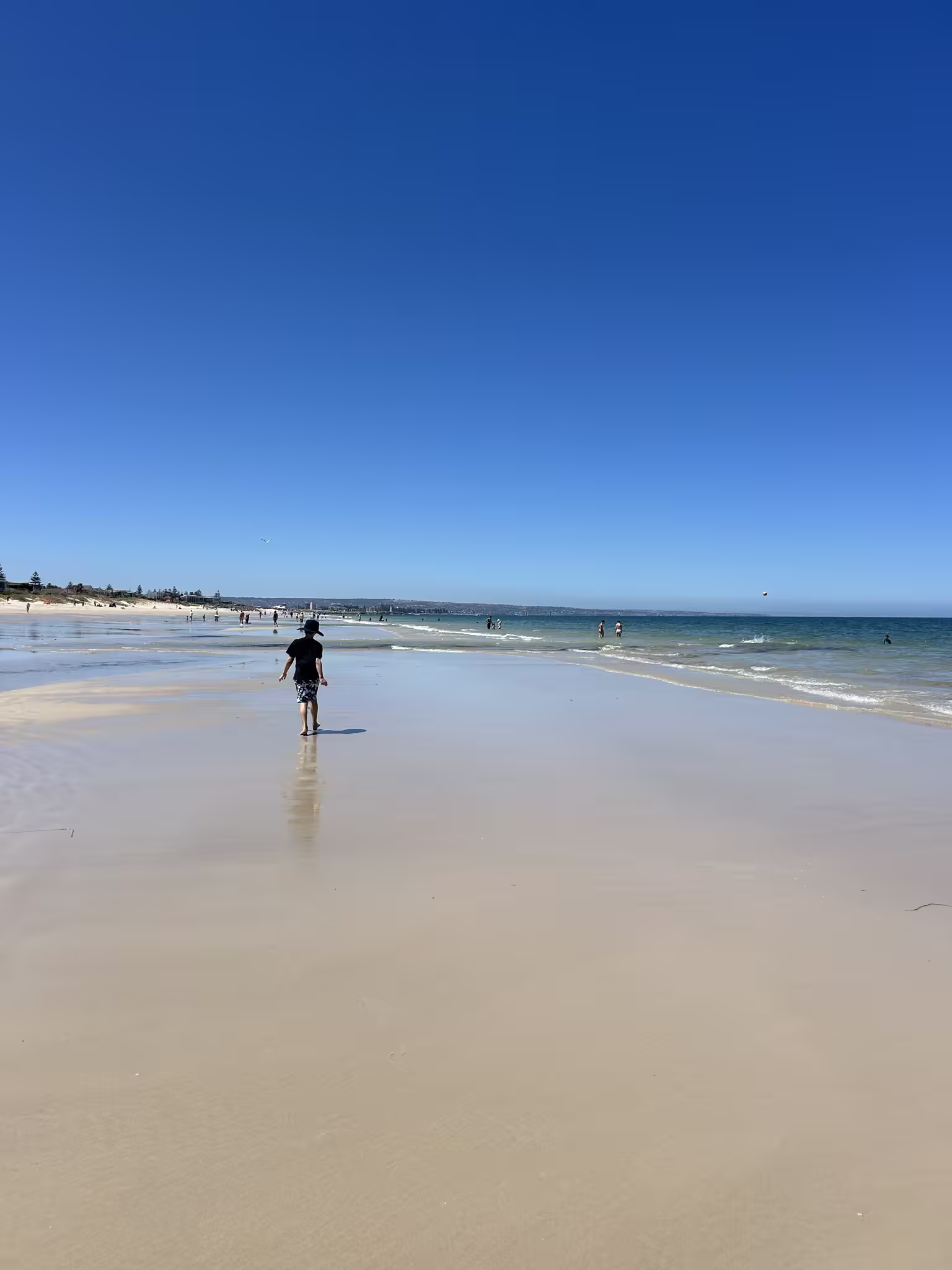 A wide beach at low tide with the shoreline stretching away