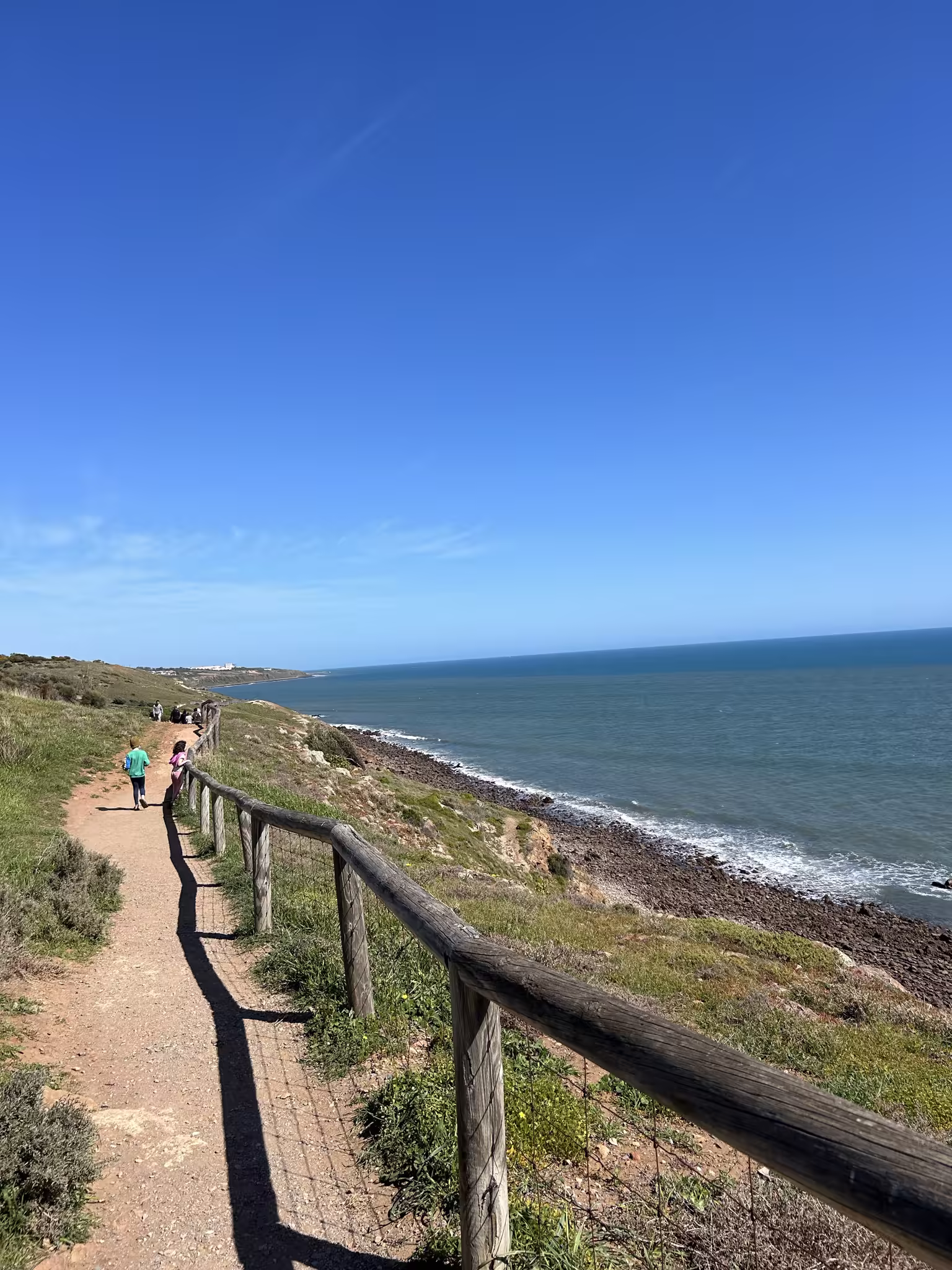 Walkers on a clifftop coastal trail above the sea